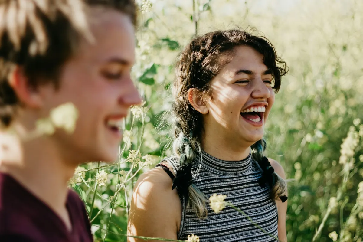 Dos jóvenes se ríen a carcajadas entre plantas