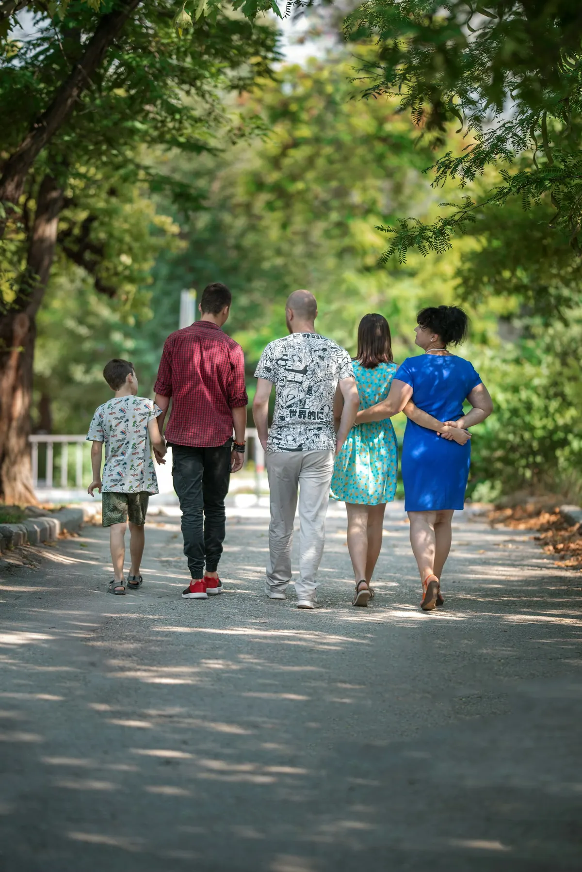 Una familia camina de espaldas por un camino arbolado